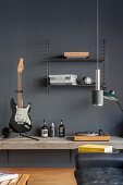 Guitar and record player on deep shelf mounted on grey wall