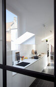 Blick durch Glastür in weiße Einbauküche