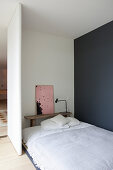 Bett und Bank in schlichtem Schlafbereich mit grau-blauer Wand