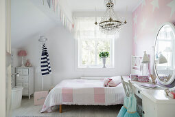 White and pink girl's bedroom with star-patterned wallpaper on wall behind bed