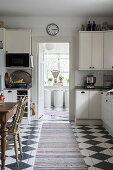 weiße Küche mit Essplatz und Schachbrettmusterboden
