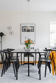 Dining table and chairs below pendant lamp and in front of poster on wall