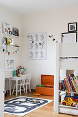 White bunk beds next to small table with two chairs below shelves in children's bedroom