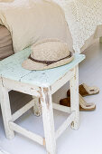 Summer hat on old stool with peeling paint next to bed