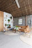 Wicker furniture and plants in living room in old, converted barn