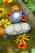Fringed floating candle holders hand-made from sardine cans and flowers floating in sandstone trough