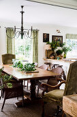 Wicker chairs and upholstered chairs around the wooden table in the rustic dining room