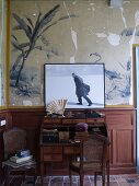 Photo of Satre on top of old writing desk leaning against old mural