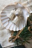 Old Christmas-tree baubles in scallop shell next to fir branch