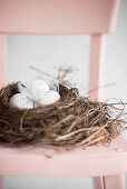 Speckled eggs in Easter nest on pink chair