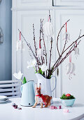 Fabric flowers hung from twigs and white tulips in jug