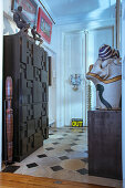 Cabinet with structured front and collection of sculptures in foyer