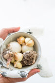 Hands holding bowl of onions and garlic in printed cloth