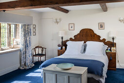 Doppelbett mit antikem Kopfteil aus Holz in weiß-blauem Schlafzimmer