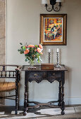 Rosenstrauß, Holzkästchen und Kerzen auf antikem Wandtisch mit Holzschnitzerei