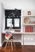Shelving with integrated desk and chair with colourful cover below window