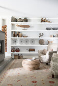 Vintage ornaments on open shelves, armchair, bamboo coffee table and log-burner in living room