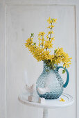 Forsythia in glass jug and bird figurines