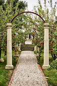 Arbor with stone columns above the gravel path in the apple orchard