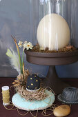 Vintage-style, Easter still-life arrangement with ostrich egg under glass cover