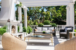 Elegant terrace with wicker armchairs, coffee table, sofa and fireplace