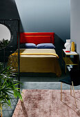 Doppelbett mit individuellem, orangefarbenem Betthaupt, Tagesdecke in Olivgrün und pflaumenfarbigen Kissen