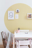 Desk and rolls of paper in basket below large yellow circle on wall