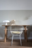 Table lamp and ceramic house on desk and classic chair in front of pale grey wall