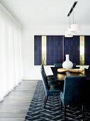 Black dining table with blue chairs, blue carpet and blue and brass artwork