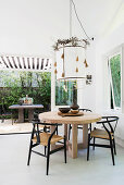 Designer table with chairs, pendant lamp above with leaf garland in the dining room