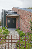 Front garden and porch built against brick façade of converted stable