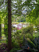 View through densely planted garden to summerhouse by pond