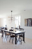 Black dining table and Windsor chairs on pale wooden floor