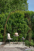 Sitzplatz unterm Bogen aus rostigen Stahlgittern im Garten