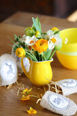 Kleiner Blumenstrauß in Krugvase und Stoffsäckchen mit Hasenmotiv auf Tisch
