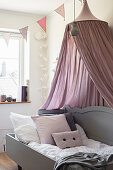 Cosy wooden bed with dusky pink canopy in child's bedroom