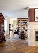 View past fireplace and antique cabinet into open-plan interior with bookcases