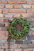 Wreath of ivy leaves and ivy flowers on old brick wall