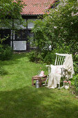 Blanket and cushions on old rocking chair and small table in garden