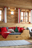 Festive cushions on wooden bed in log cabin