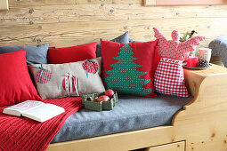 Festive cushions and angel cushion on wooden bed in log cabin