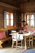 Festively decorated dining table and bench in log cabin