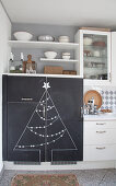 Kitchen cupboards with Christmas tree drawn on chalkboard doors