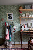Clothes rail and old desk against green wallpaper