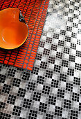 Orange bowl on bench on black-and-white mosaic floor