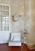 Stylised bull head on distressed wall above easy chair