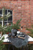 Arrangement of black Christmas decorations and pine branches outside brick house