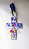 Blue patterned cross decorated with pompom and feathers