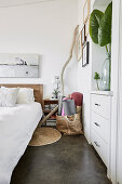 Bed and built-in chest of drawers in the bedroom with white walls
