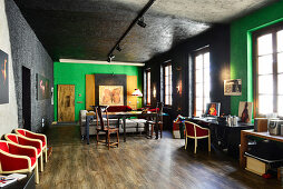 Red chairs, dining table and desk in renovated loft apartment with black and green walls